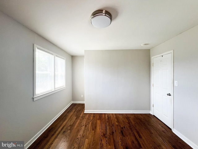 unfurnished room with dark wood-type flooring