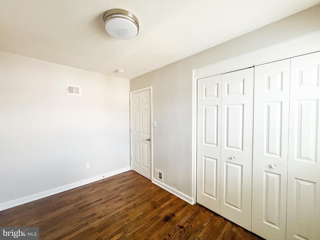 unfurnished bedroom featuring a closet and dark wood-type flooring