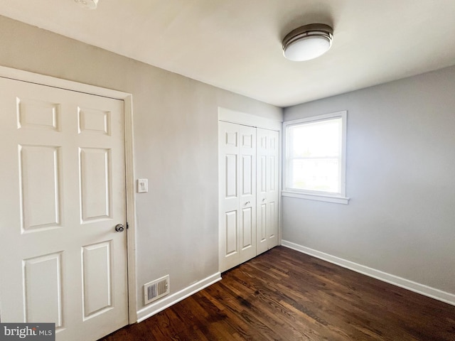 unfurnished bedroom with dark hardwood / wood-style flooring and a closet