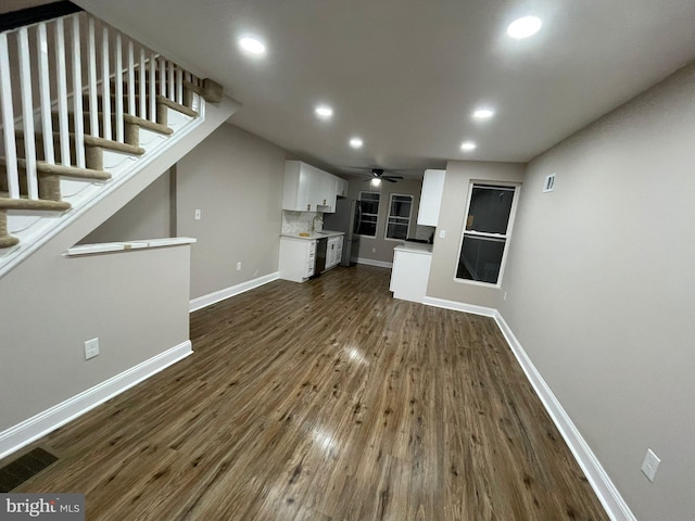 unfurnished living room with ceiling fan and dark wood-type flooring