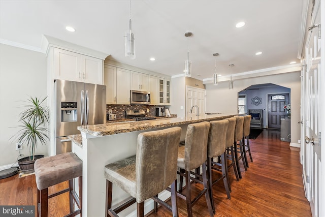 kitchen featuring glass insert cabinets, pendant lighting, appliances with stainless steel finishes, and light stone counters