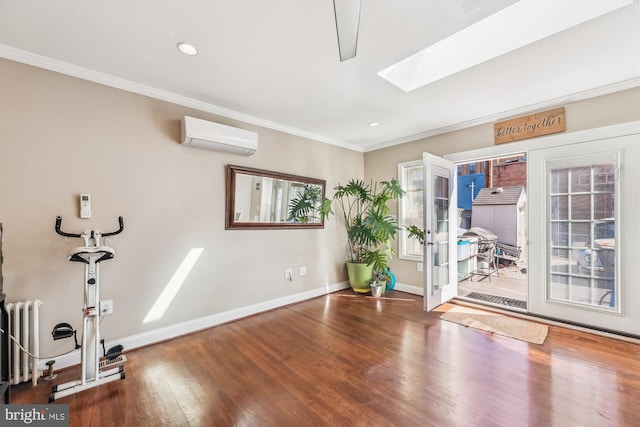 exercise area featuring a wall unit AC, a skylight, wood finished floors, ornamental molding, and radiator