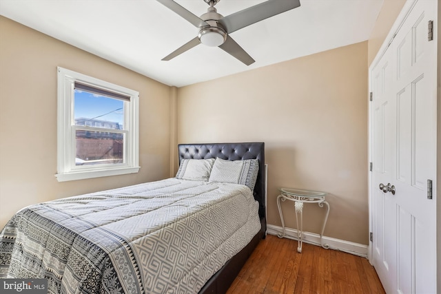 bedroom with dark wood-type flooring, ceiling fan, and baseboards