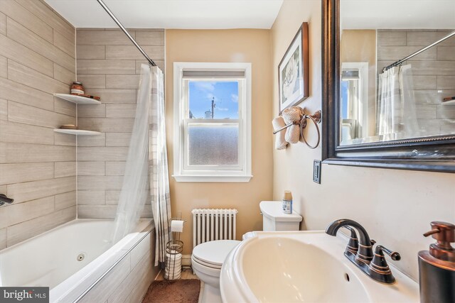 bathroom featuring radiator, shower / bath combination with curtain, toilet, and a sink