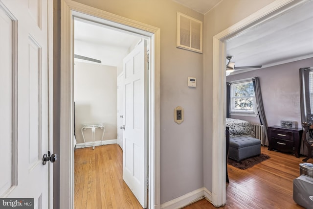 hallway featuring light wood-style flooring, visible vents, and baseboards