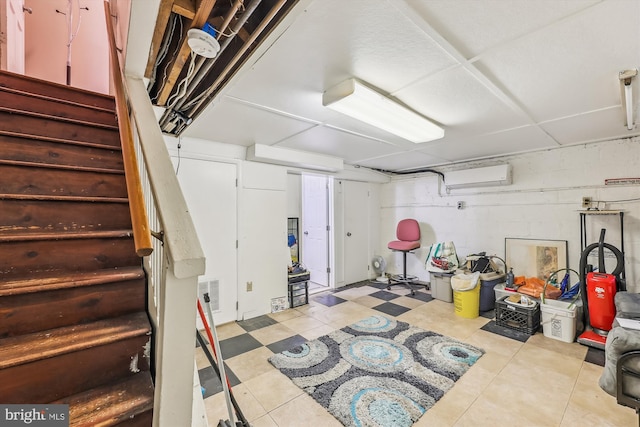 finished basement with concrete block wall, visible vents, stairway, and light floors