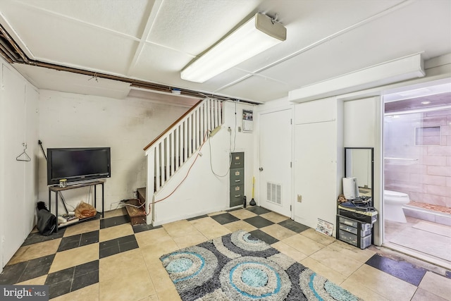 finished below grade area with visible vents, stairway, and tile patterned floors