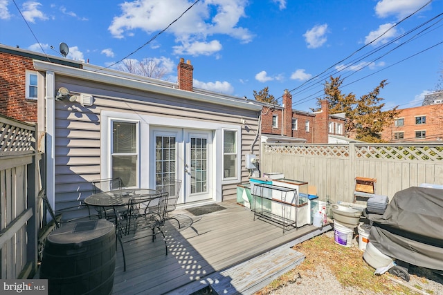 wooden deck with outdoor dining space, french doors, and fence