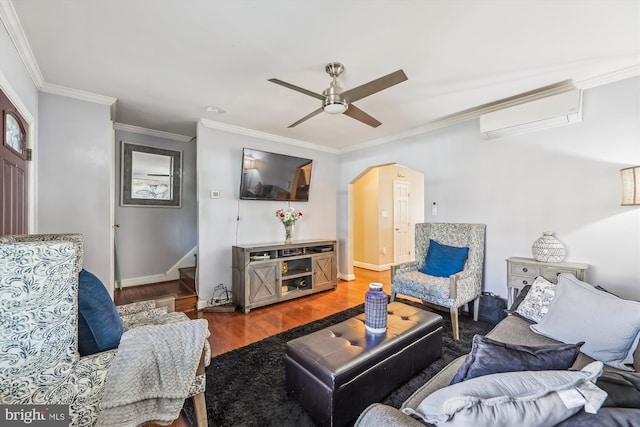 living room with arched walkways, ceiling fan, ornamental molding, wood finished floors, and a wall mounted air conditioner