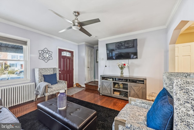 living room with dark wood-style floors, ornamental molding, arched walkways, and radiator