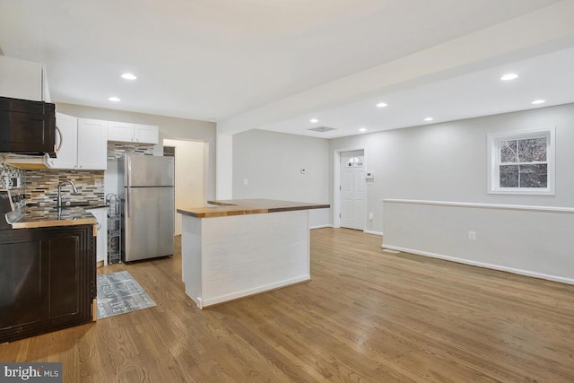 kitchen featuring wood counters, light hardwood / wood-style floors, stainless steel refrigerator, and white cabinetry