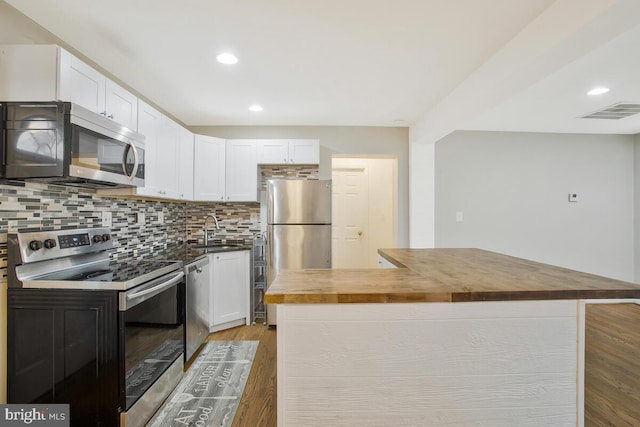 kitchen featuring white cabinetry, wooden counters, stainless steel appliances, and sink