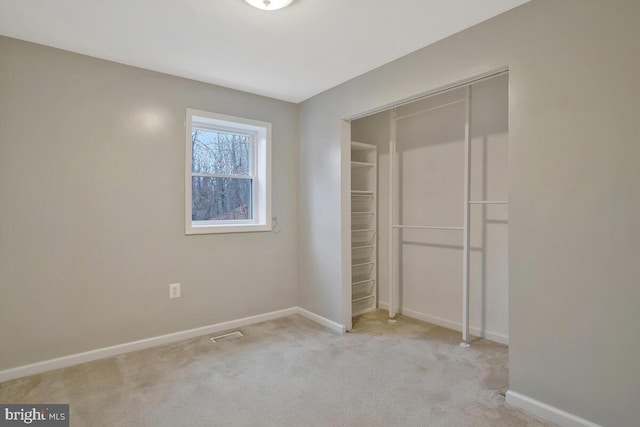 unfurnished bedroom with light colored carpet and a closet