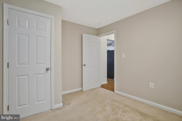 unfurnished bedroom with light carpet and fridge