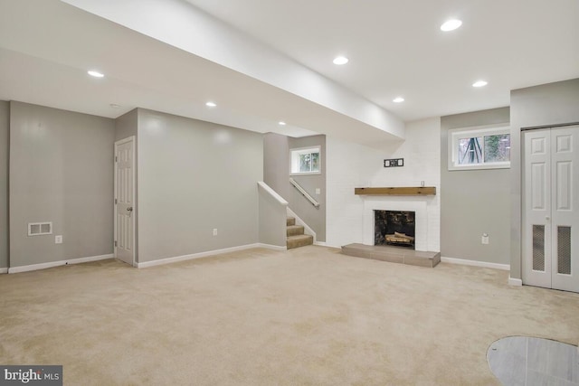 unfurnished living room featuring a large fireplace and light colored carpet