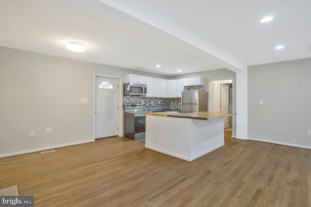 kitchen with a center island, white cabinets, light wood-type flooring, butcher block countertops, and stainless steel appliances