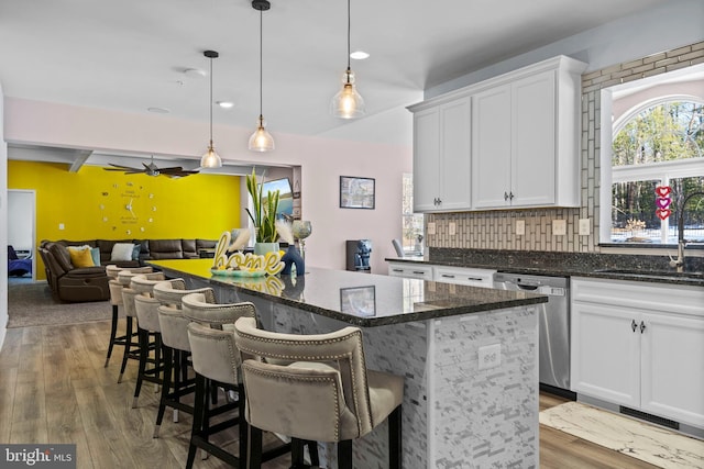 kitchen featuring a center island, sink, stainless steel dishwasher, pendant lighting, and white cabinets