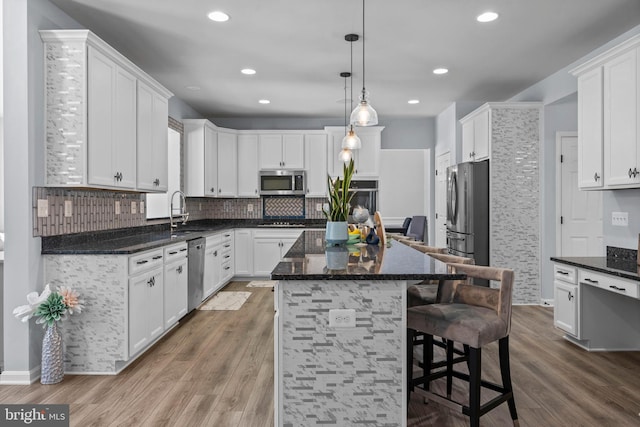 kitchen featuring a center island, white cabinets, hanging light fixtures, dark hardwood / wood-style flooring, and stainless steel appliances