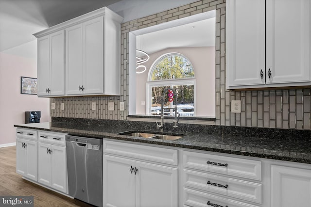 kitchen with dishwasher, sink, tasteful backsplash, dark stone countertops, and white cabinets