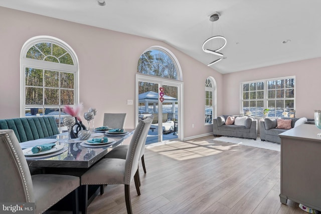 dining space featuring a wealth of natural light, lofted ceiling, and light wood-type flooring