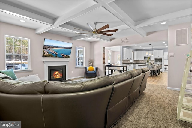 carpeted living room with ceiling fan, beamed ceiling, and coffered ceiling