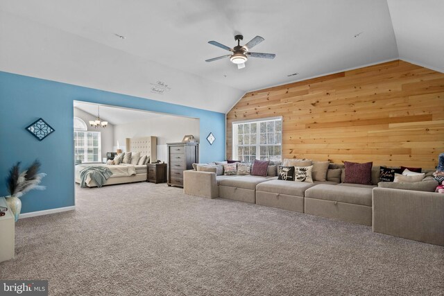 living room with ceiling fan with notable chandelier, vaulted ceiling, and wood walls