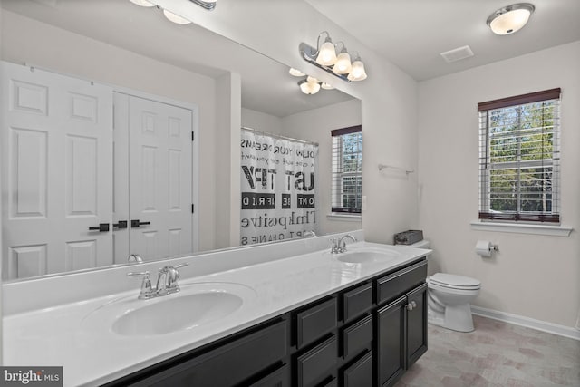 bathroom featuring walk in shower, vanity, toilet, and a wealth of natural light