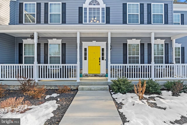 snow covered property entrance featuring a porch