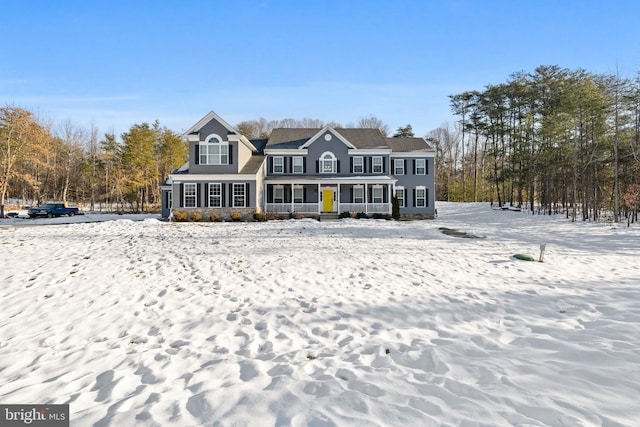 snow covered rear of property featuring covered porch