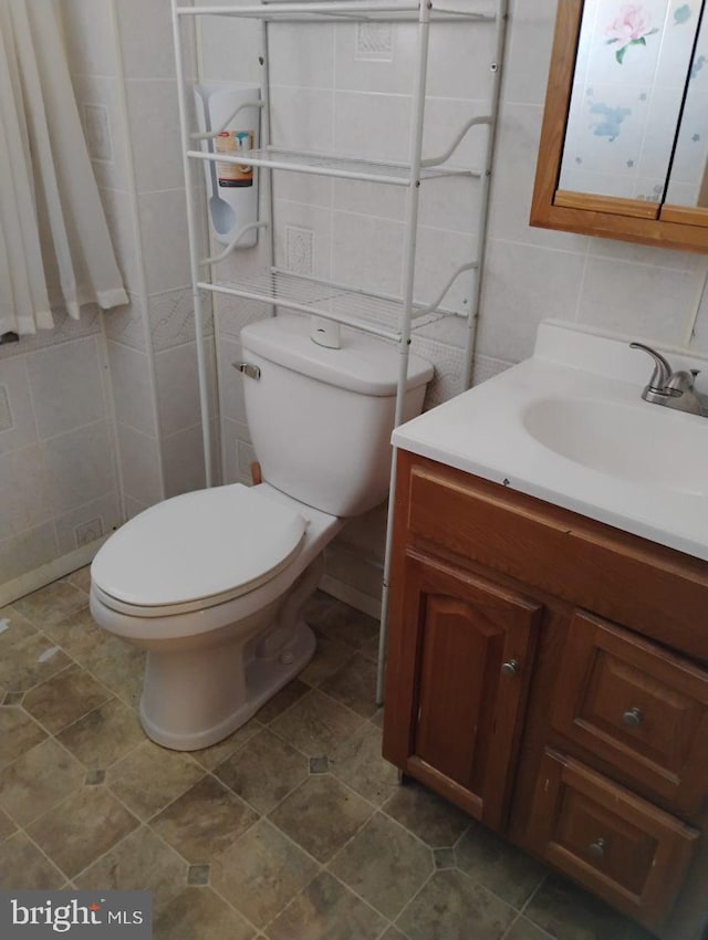 bathroom with vanity, tile walls, and toilet