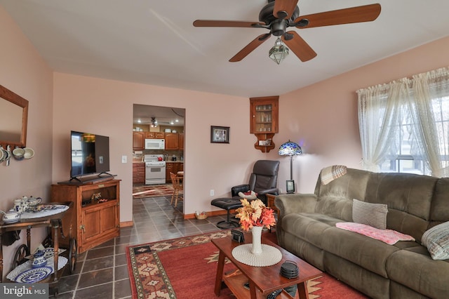 living room with ceiling fan and dark tile patterned flooring