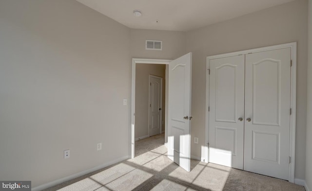 unfurnished bedroom with light colored carpet and a closet