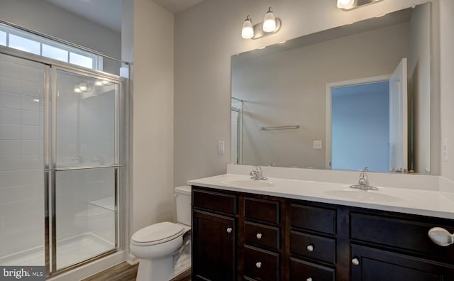 bathroom featuring a shower with door, vanity, wood-type flooring, and toilet