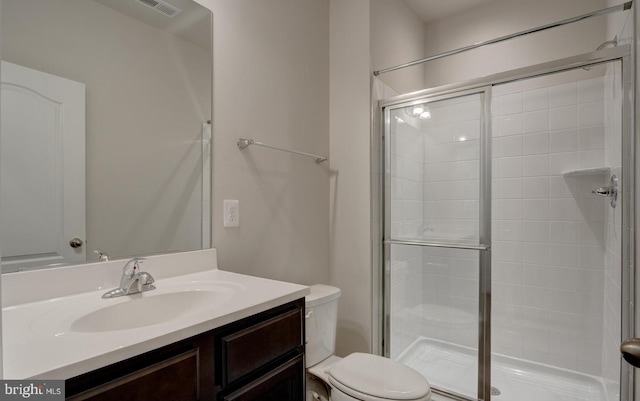 bathroom featuring vanity, toilet, and a shower with shower door