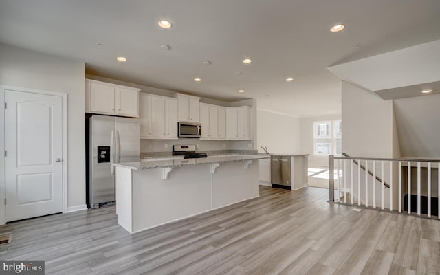 kitchen featuring light stone counters, a center island, white cabinets, and appliances with stainless steel finishes