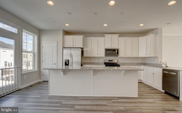 kitchen featuring a kitchen island, light stone countertops, and appliances with stainless steel finishes