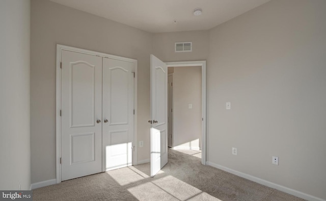 unfurnished bedroom featuring light carpet and a closet