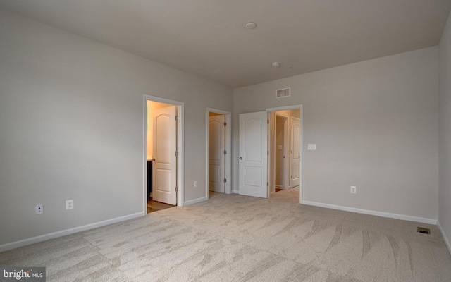 unfurnished bedroom with ensuite bath and light colored carpet