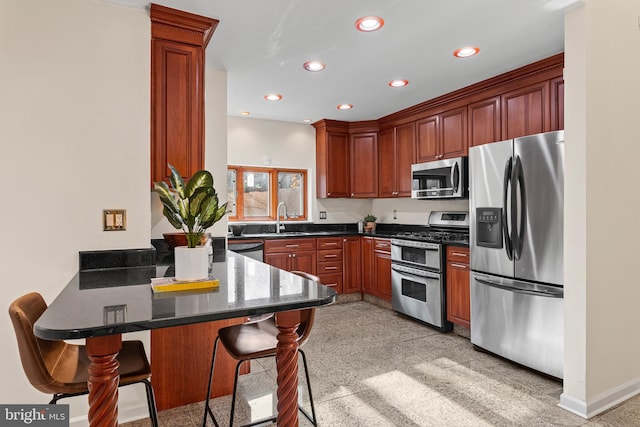 kitchen with a breakfast bar, dark stone counters, sink, kitchen peninsula, and stainless steel appliances