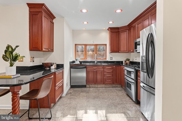 kitchen with kitchen peninsula, a kitchen breakfast bar, stainless steel appliances, sink, and dark stone countertops