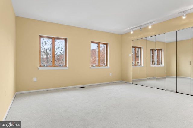 carpeted empty room featuring rail lighting