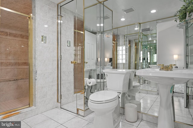 bathroom with toilet, tile patterned floors, a shower with door, and tile walls