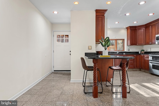 kitchen featuring a breakfast bar area, kitchen peninsula, sink, and stainless steel stove