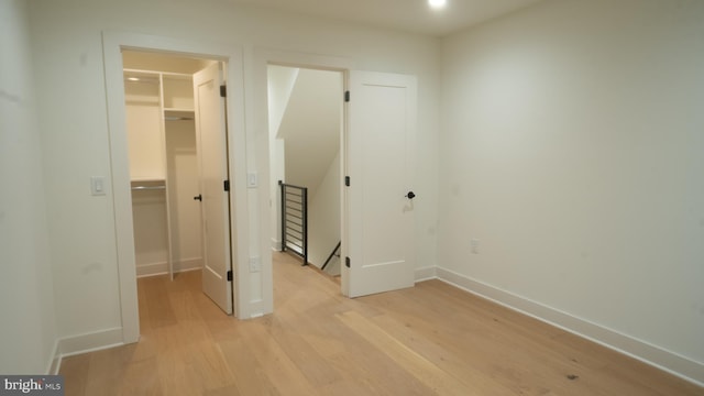 unfurnished bedroom with a walk in closet, a closet, and light hardwood / wood-style floors