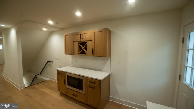 kitchen with light hardwood / wood-style floors, lofted ceiling, built in microwave, and tasteful backsplash