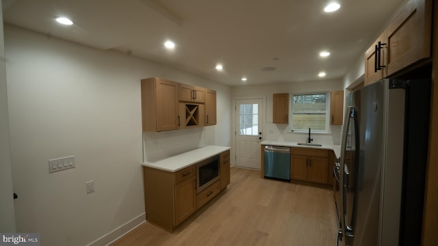 kitchen with tasteful backsplash, sink, light hardwood / wood-style flooring, and appliances with stainless steel finishes