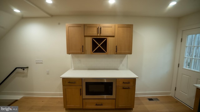 kitchen with light hardwood / wood-style floors, backsplash, and built in microwave