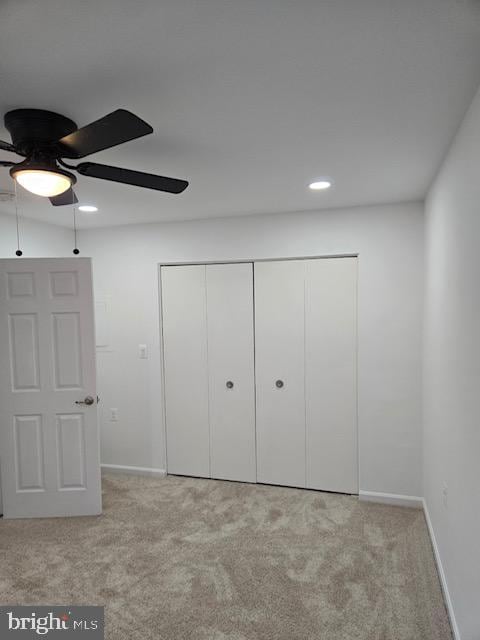 unfurnished bedroom with ceiling fan, light carpet, and a closet