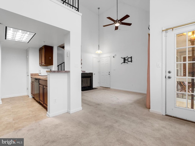 kitchen featuring stainless steel dishwasher, ceiling fan, a towering ceiling, and light carpet