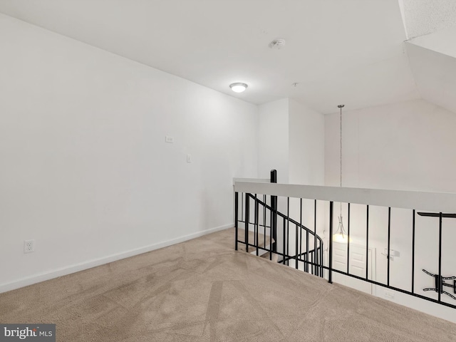 spare room featuring light colored carpet and vaulted ceiling